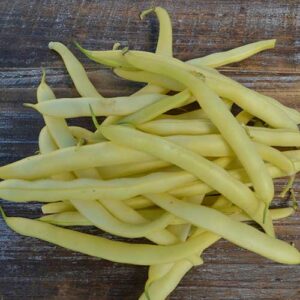 A pile of long, yellow beans on a wooden surface