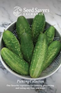 A collection of cucumbers sit in a metal strainer on a marble surface. The Seed Savers Exchange logo is overlayed at the top. Text at the bottom says, "Pickling Collection: Our favorite vegetables for canning, preserving, and eating any time you want!"