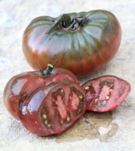 A deep purple 'Black Krim' tomato with a sliced tomato in front of it