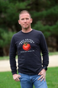 A man poses wearing a long sleeve shirt with a tomato on it