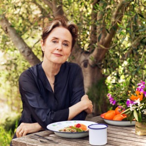 A woman sits at a table with a plate of food in front of her.
