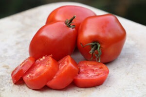 Three red 'Amish Paste' tomatoes and four tomato slices on a countertop