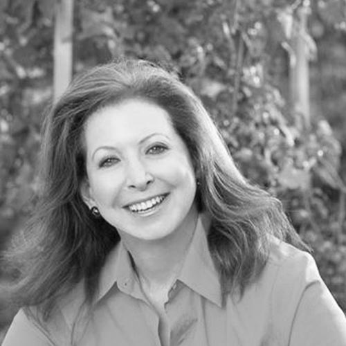 Black and white photo of a woman smiling into camera.