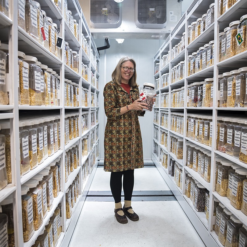 Woman standing in the middle of an aisle with shelves on both sides of her.