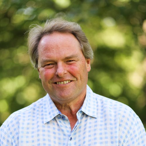 Man smiling in light blue and white checkered button down shirt.