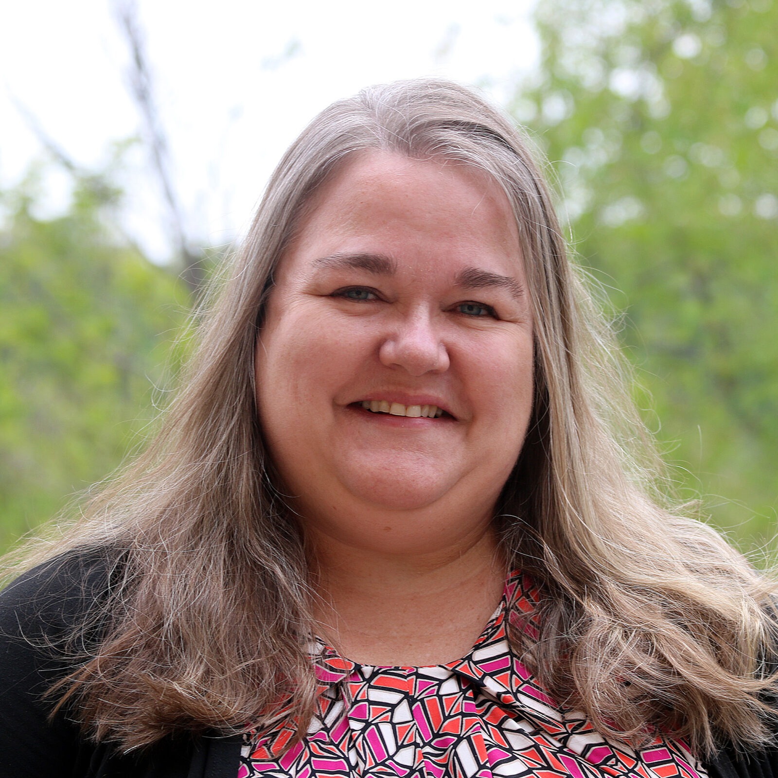 Woman with long hair smiling into camera.