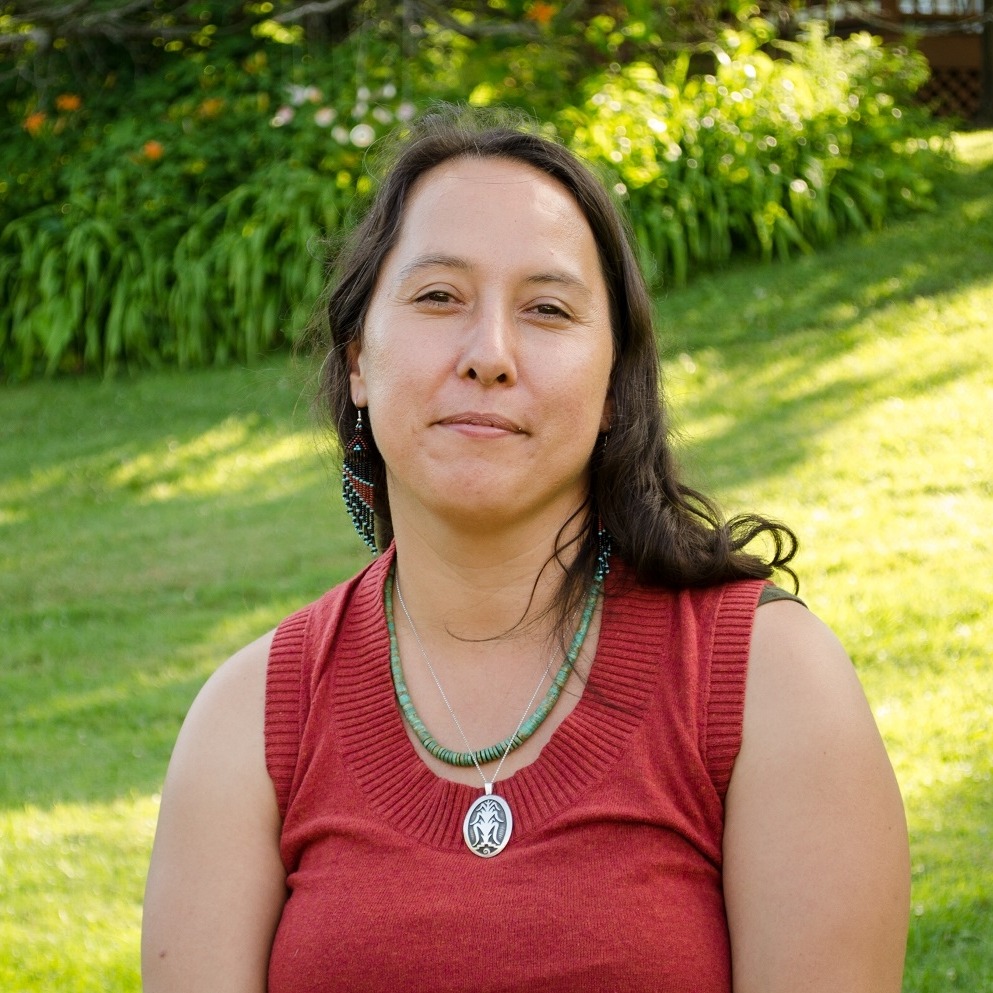 A woman in a red top poses outdoors.