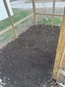 A small, fenced in garden with fresh compost added to the soil