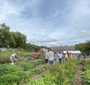 A group of people gather in a garden for a lecture.