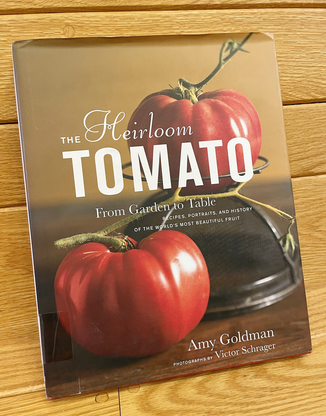 The book 'The Heirloom Tomato' by Amy Goldman, featuring two red tomatoes on its cover.