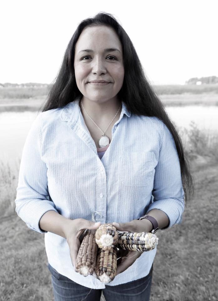 Woman holds corn cobs.