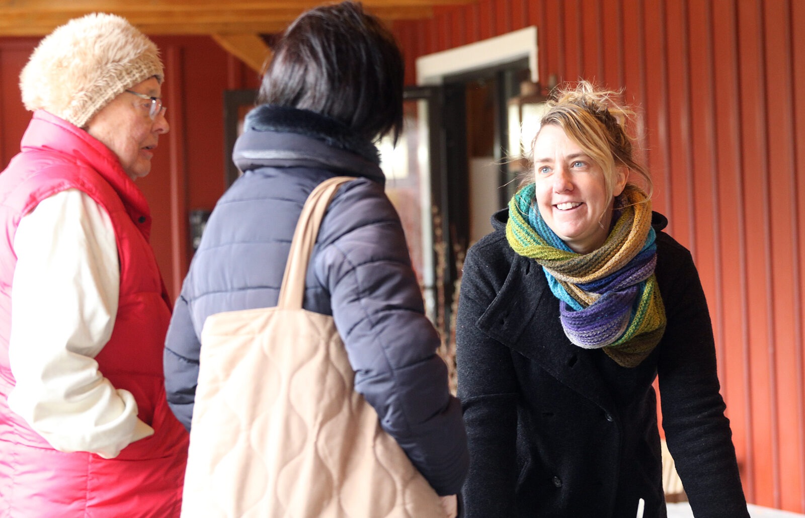 Three people standing in coats and scarves.