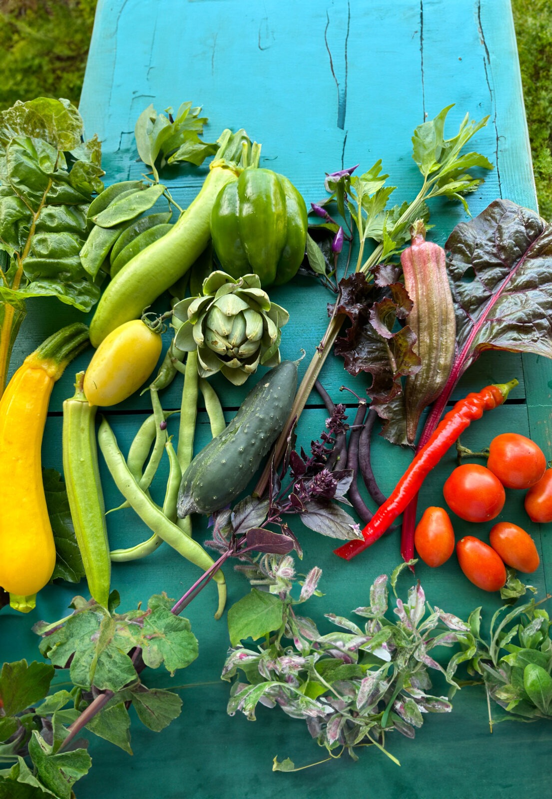 A variety of colorful vegetables on a teal blue table.