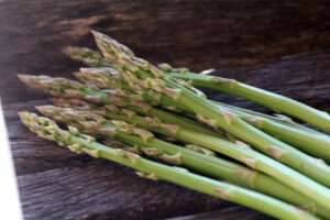 A bunch of 'Three Pound Coffee Can' asparagus spears laying on a wooden bench