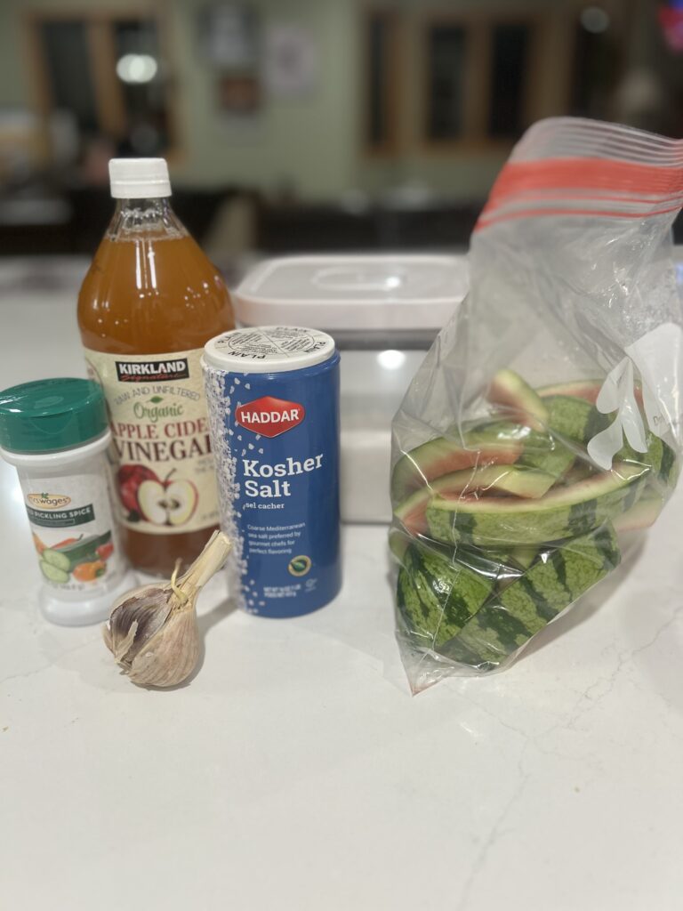An assortment of ingredients for pickled watermelon rind on a white countertop