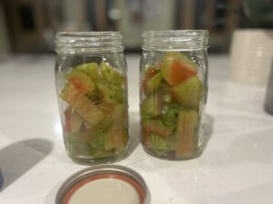 Two large glass jars filled with pieces of soften watermelon rinds on a white counter top