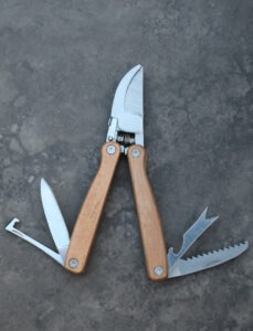A gardening pocket tool with pruners, weeders, and several knives
