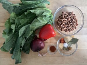 A spread of ingredients including collard greens, black-eyed peas, pepper, onion, and various spices