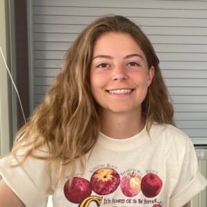 A woman wearing an apple t-shirt smiles to camera.