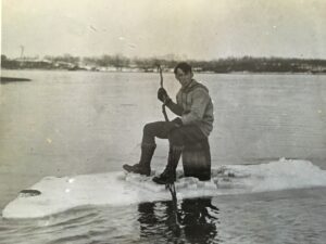 John Withee as a young man sitting on a large floating piece of ice in a lake.