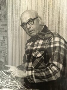 An older John Withee in a plaid shirt shelling dried beans