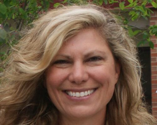 Woman with blonde hair smiles into camera.