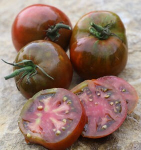 Three blackish-red tomatoes and three tomato slices 