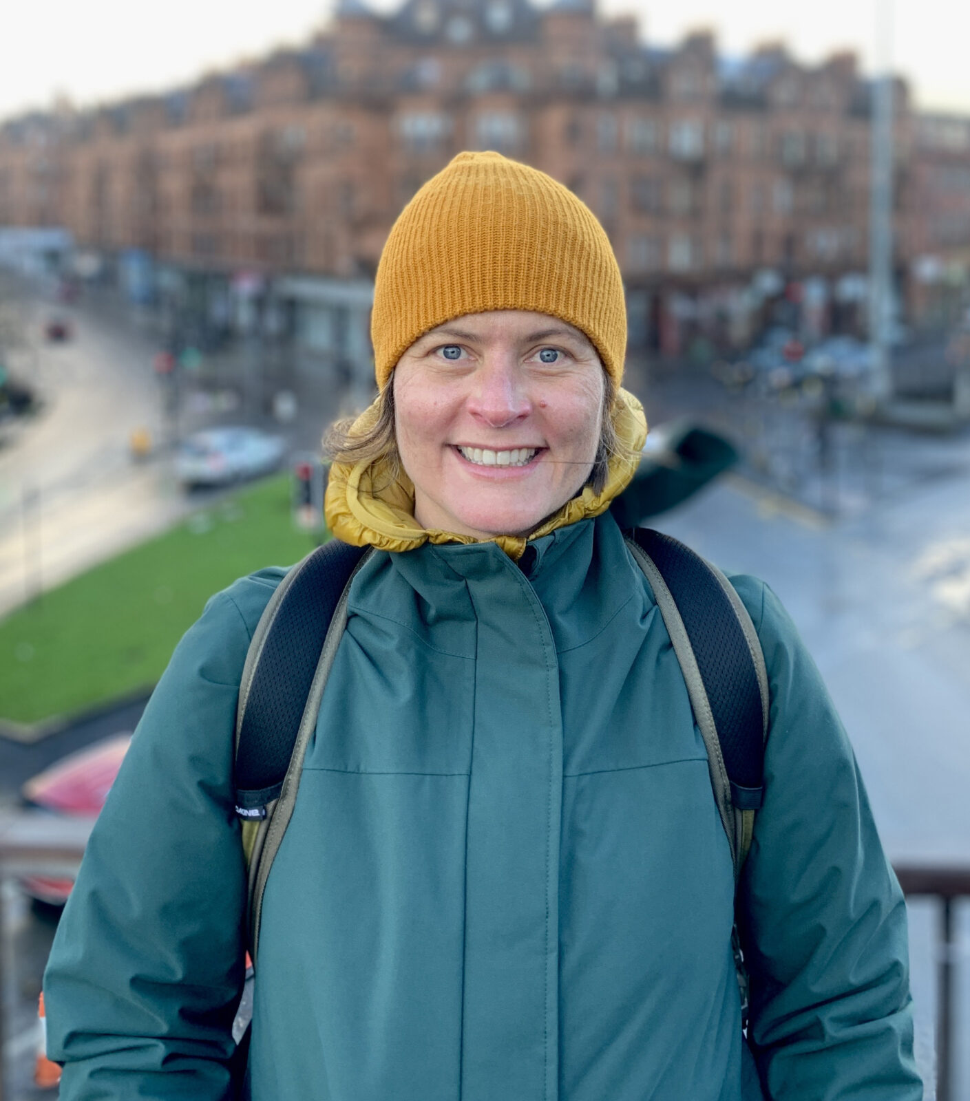 smiling woman in yellow stocking had and teal jacket