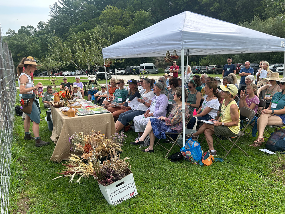 A crowd sits under a tent for an outdoor class.