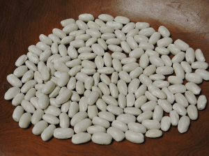 A pile of oval white dry beans in a wooden bowl