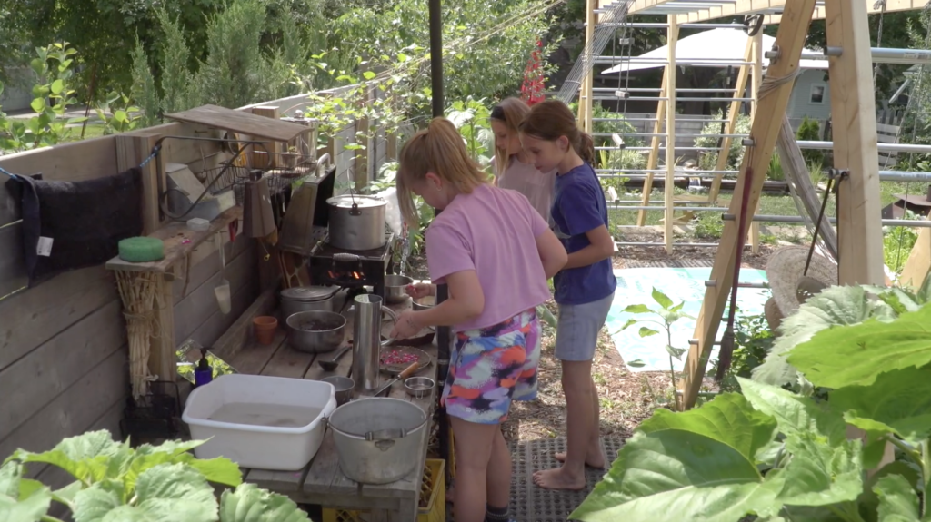 Several children prepare food on an outdoor bench
