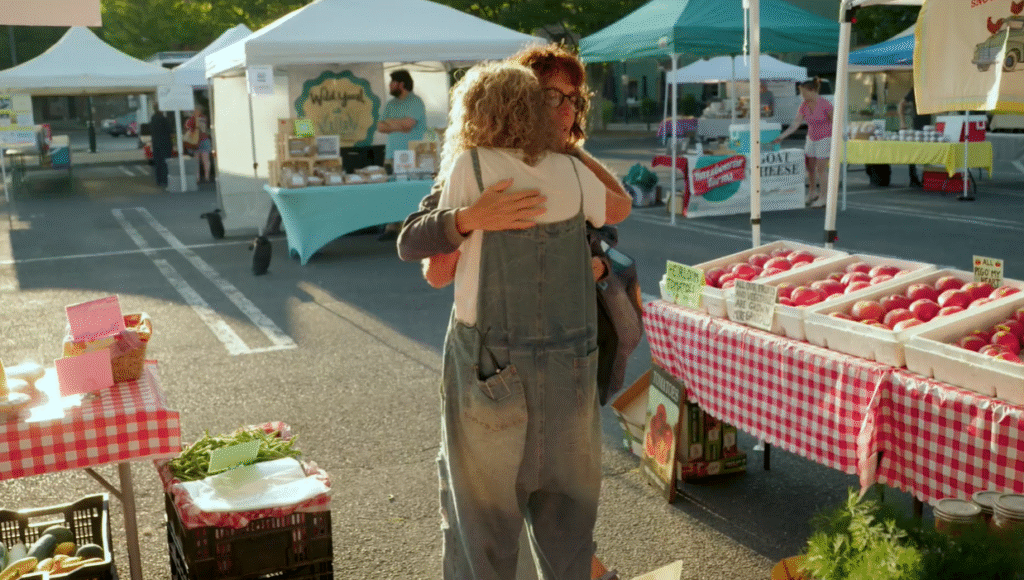 Two women hug at a farmer's market booth