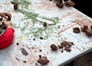 A messy table with bits of clay and a green powder spread across it